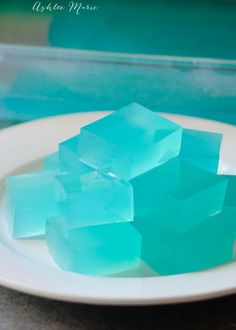 a white plate topped with blue ice cubes on top of a counter next to a plastic container