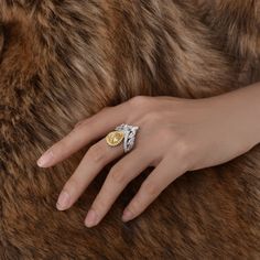 a woman's hand with a gold and silver ring on top of a fur