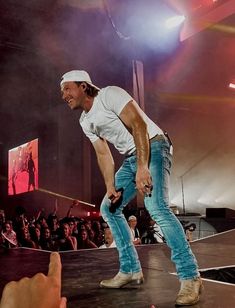 a man standing on top of a stage holding a microphone in front of an audience