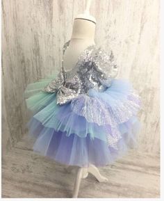 This dress has a silver sequin top and bow and a mermaid colored tutu skirt. Silver Princess Dress For Dress-up, Princess Style Sequined Tutu Dress For Dress-up, Mermaid Tutu Dress In Tulle For Party, Mermaid Tulle Tutu Dress For Party, Blue Tutu Dress For Holiday Parties, Party Princess Dress With Sequins And Glitter Tulle, Princess Style Tulle Mermaid Dress For Party, Princess Style Sequin Party Dress, Princess Style Sequin Dress For Dress-up Occasions