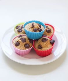 four muffins on a plate with chocolate chips