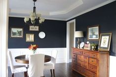 a dining room with blue walls and white chairs in the corner, along with pictures on the wall