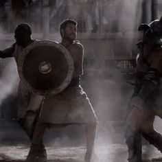 two men dressed in roman armor, one holding a shield