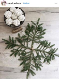 a pine tree branch with white balls and twine on it next to a bowl of needles