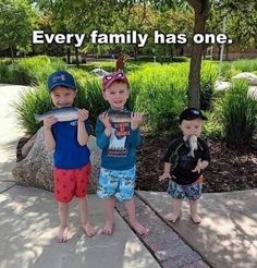 three young boys standing next to each other on a sidewalk holding fish in their hands