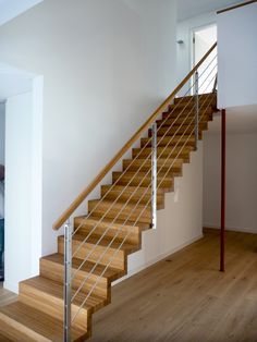 a wooden stair case with metal handrails in an empty room next to a white wall