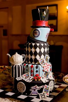 a multi - tiered cake decorated with playing cards and other items on a checkered table