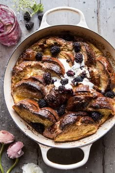 a pan filled with fruit and cream on top of a wooden table next to flowers