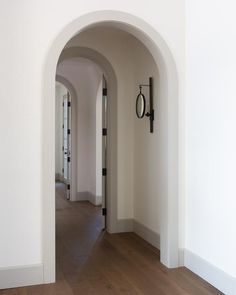 an archway leading to another room with wood floors and white walls, along with a clock on the wall