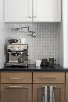 an espresso machine sitting on top of a counter next to white cupboards