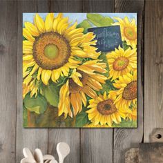 sunflowers painted on a wooden wall with a chalkboard in the center and two spoons next to it