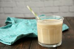 a glass filled with milk sitting on top of a wooden table next to a napkin