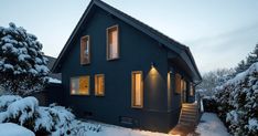 a house with snow on the ground and stairs leading up to it's windows