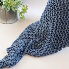 a blue knitted scarf laying on top of a white surface