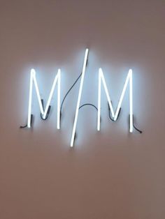 a neon sign that says mam on the side of a wall with wires attached to it