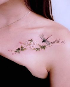 a woman's chest with flowers and a dragonfly tattoo on her left shoulder