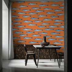 an orange wallpaper with fish on it and two chairs in front of the table