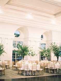 the tables are set up with white linens and greenery for an elegant wedding reception