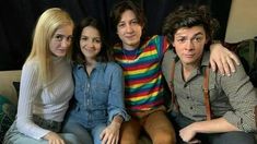 four people sitting on a couch posing for the camera