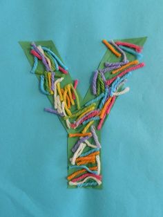 the letter y is made out of colored thread and yarns on a blue background