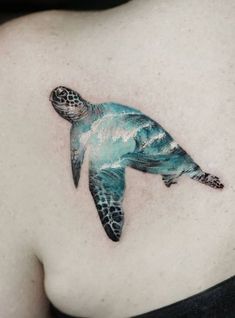 a green turtle tattoo on the back of a woman's left shoulder and chest