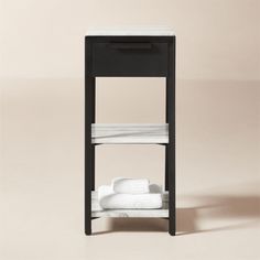 a black and white shelf with two folded towels on it's sides, against a beige background