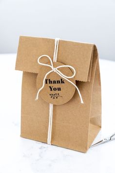 a brown paper bag with a thank you tag tied around the front and side of it