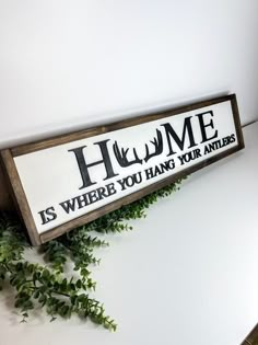 a wooden sign that says home is where you hang your antlers