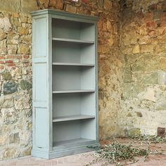 an empty bookcase sitting in front of a stone wall