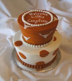 two tiered cake with white and brown polka dots on the bottom, decorated with words welcome little kingdom