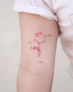 a woman's arm with pink flowers on it and the letter p tattooed in