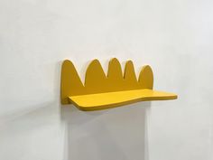 a yellow shelf mounted to the side of a white wall with a crown on it