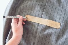 a person holding a pen and pointing to a piece of leather