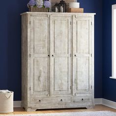 a white armoire in a room with blue walls