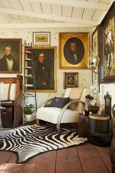 a living room with zebra print rug and pictures on the wall, including an antique chair