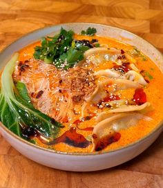 a white bowl filled with soup on top of a wooden table