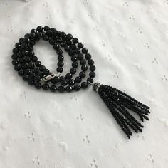 "Black Tassel Necklace, Long Black Onyx Necklace, Gemstone Necklace.  There's only one.   A trendy necklace with a beaded tassel and a sparkling rhinestone bead cap.  The necklace is made of black onyx beads  - round and faceted beads for lots of sparkle.  The tassel is made of jet black glass beads.    The necklace is 36\" long, plus another 3\" for the tassel.   Even though it's long enough to slip over your head, I have included a sterling lobster clasp.   The necklace shown here will be the Handmade Black Long Crystal Necklace, Handmade Black Crystal Long Necklace, Adjustable Black Long Crystal Necklace, Black Long Faceted Beaded Necklace, Three Strand Pearl Necklace, Adjustable Black Tassel Necklace, Trendy Necklace, Black Onyx Necklace, Onyx Necklace