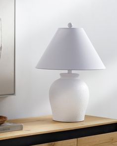 a white lamp sitting on top of a wooden table