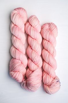 three skeins of pink yarn on a white surface