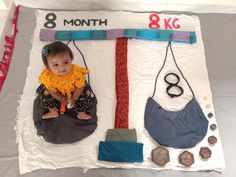 a baby sitting on top of a table next to a tie and other items that are made out of paper