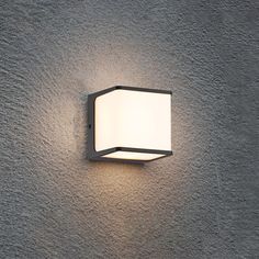 a square light mounted on the side of a wall with a white lamp in it