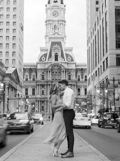 a man and woman standing on the sidewalk in front of a building with a clock tower