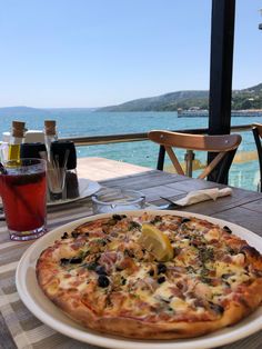 a pizza sitting on top of a white plate next to a glass of wine and water