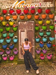 a woman standing in front of a building with potted plants on the outside wall