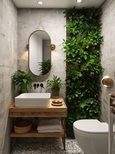 a white toilet sitting next to a sink in a bathroom under a green plant wall