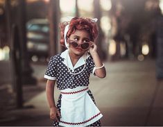 a woman with red hair and polka dot dress on talking on her cell phone while walking down the street