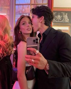 a man and woman taking a selfie in front of a mirror with their cell phone