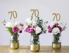 three mason jars with flowers and gold numbers