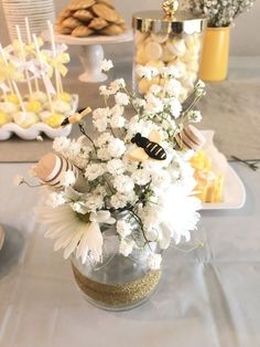 a vase filled with lots of white flowers on top of a table next to other desserts