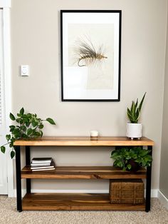 a wooden shelf with plants on it in front of a framed photo and potted plant